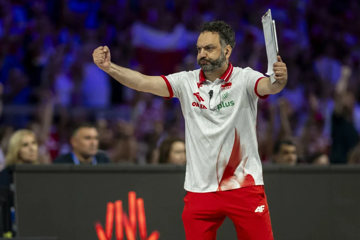 Stefano Lavarini, trener siatkarek Polski, w białej koszulce z tablicą taktyczną, na tle publiczności