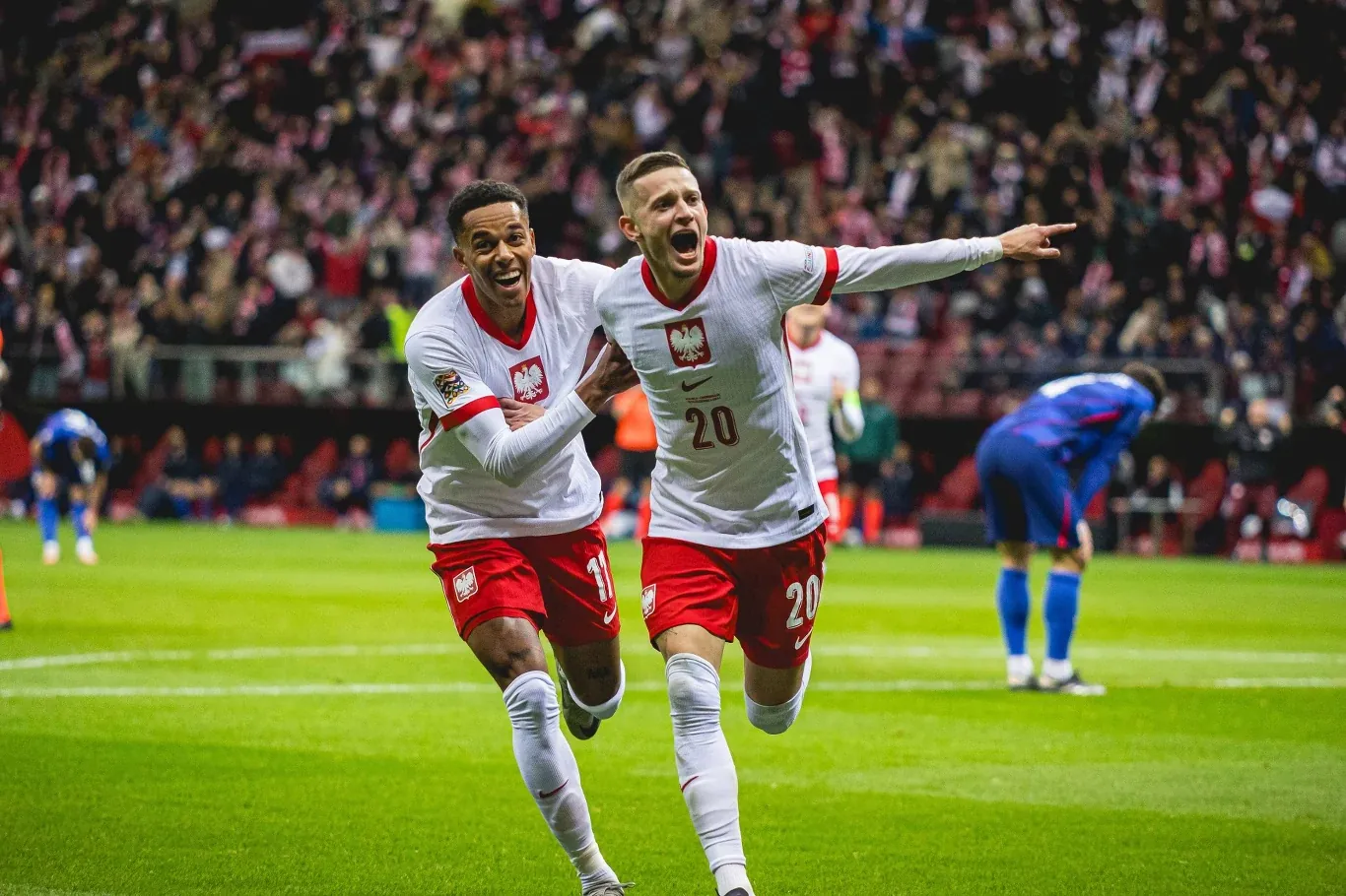 Michael Ameyaw (z lewej) i drugi piłkarz Polski w biało-czerwonych strojach na murawie stadionu.